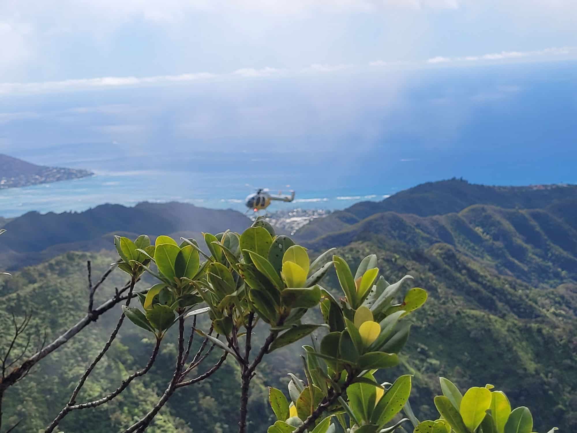 Helicopter flying along a ridge in Oahu.